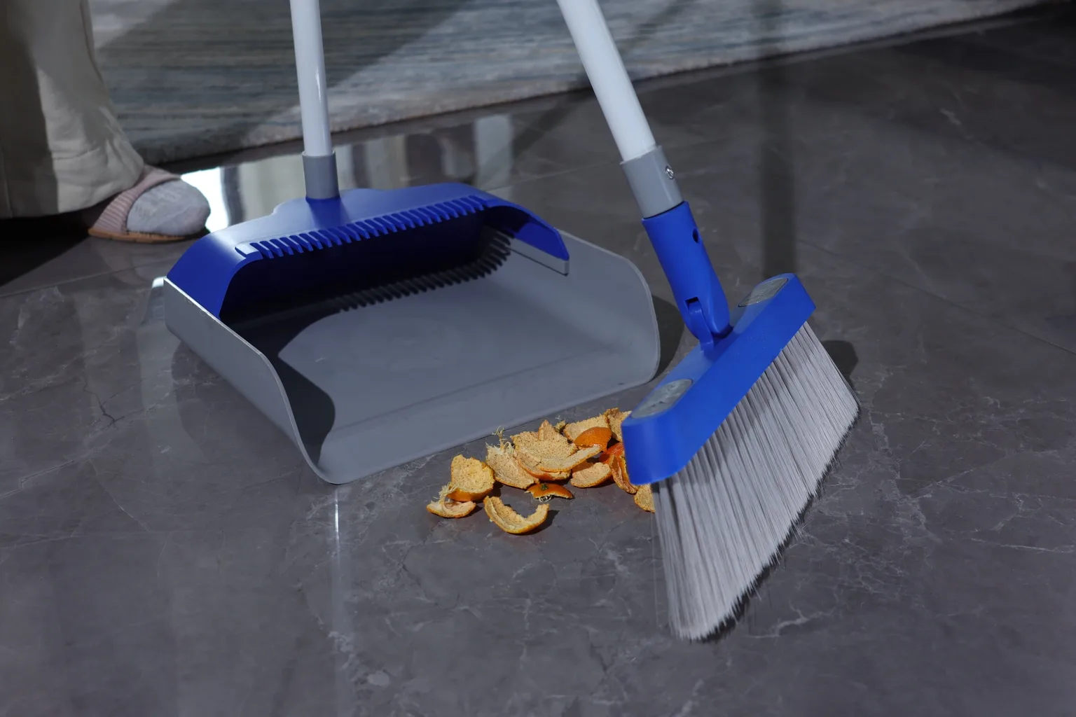 Broom and dustpan cleaning a tiled floor